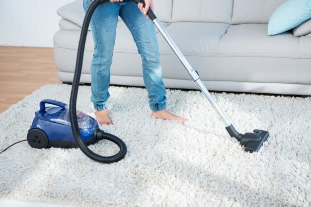 woman cleaning carpet using vacuum cleaner