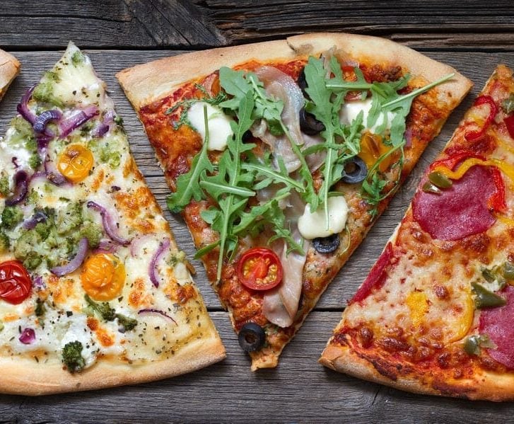 different flavored pizza slices on wooden board