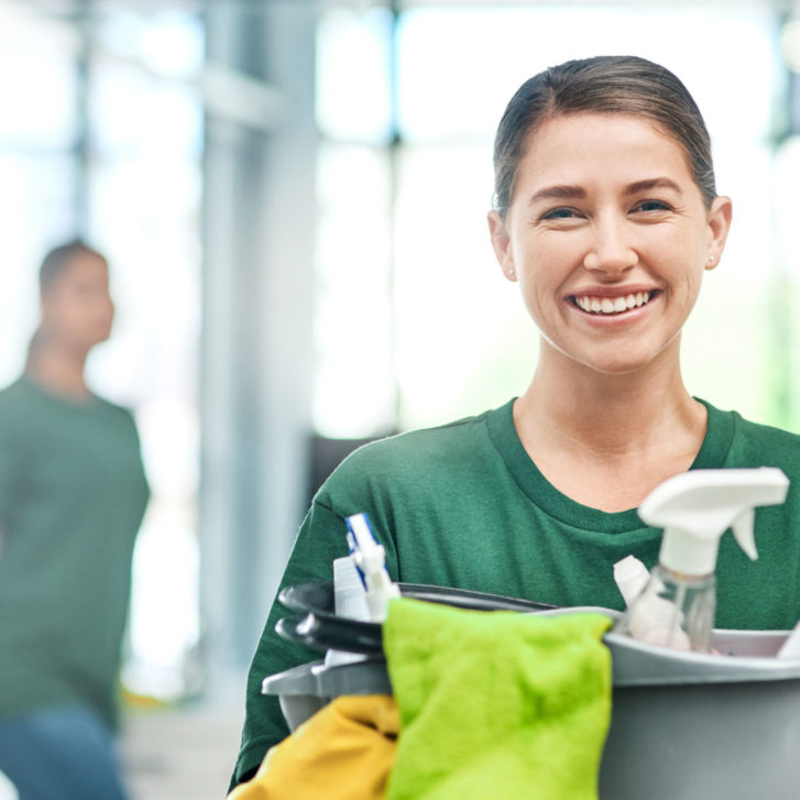 woman wearing green shirt cleaning an office with her colleague