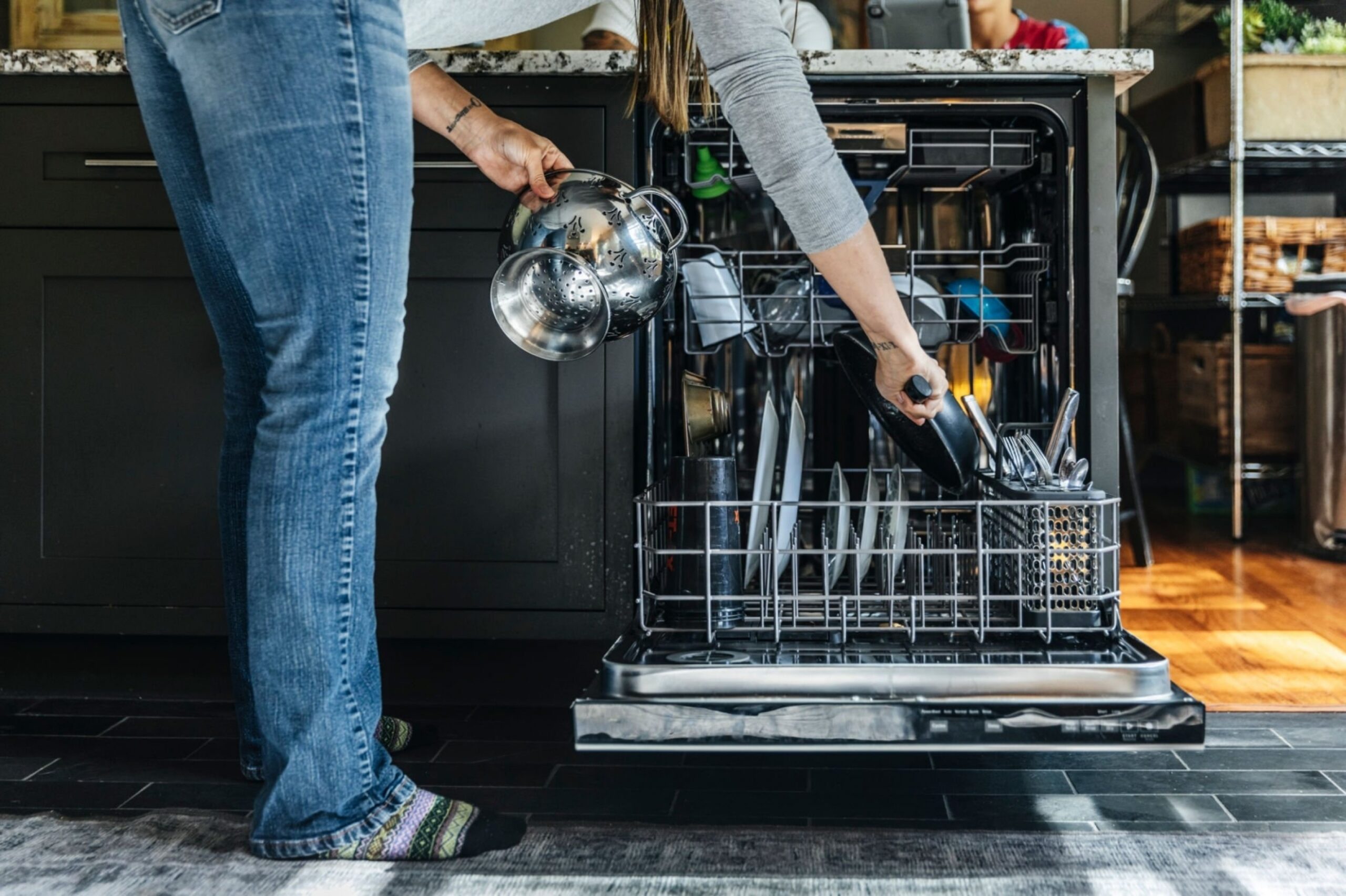 Woman arranging utensils in dishwasher at home