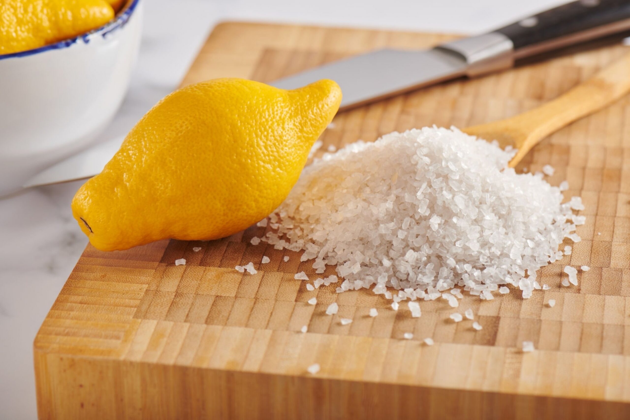 Lemon and pile of coarse sea salt on cutting board