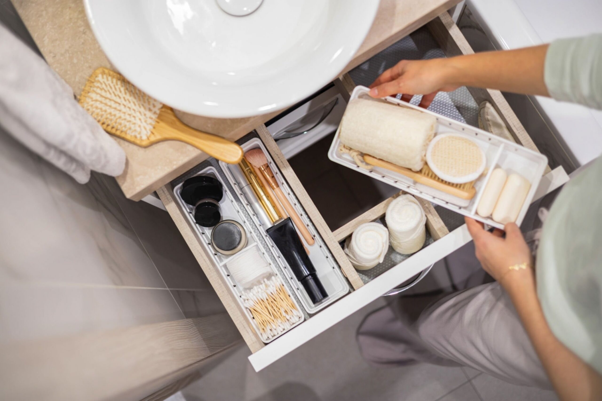 Woman neatly organizing bathroom amenities and toiletries in drawer