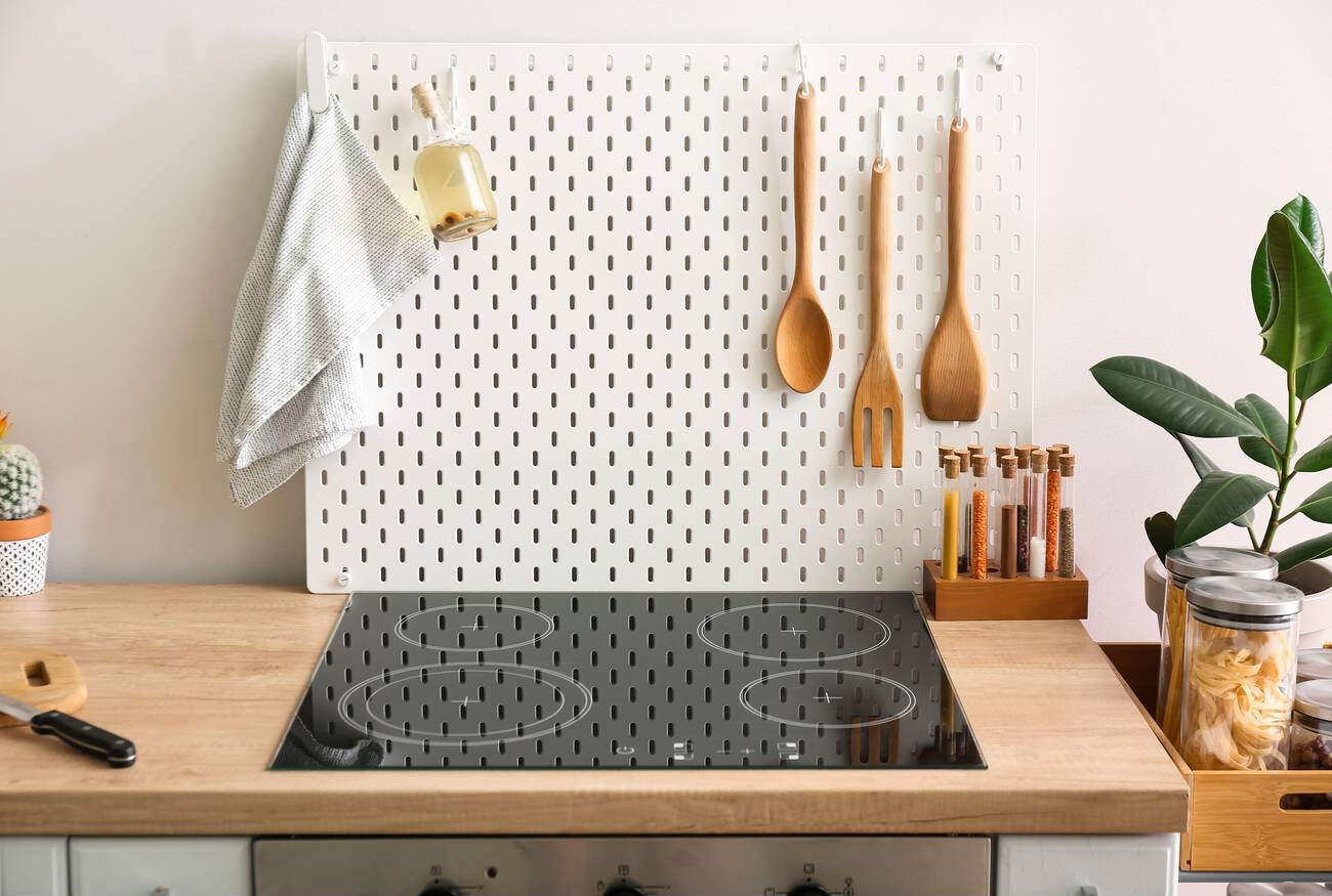 Peg board with napkin, bottle of oil and spatulas on kitchen counter