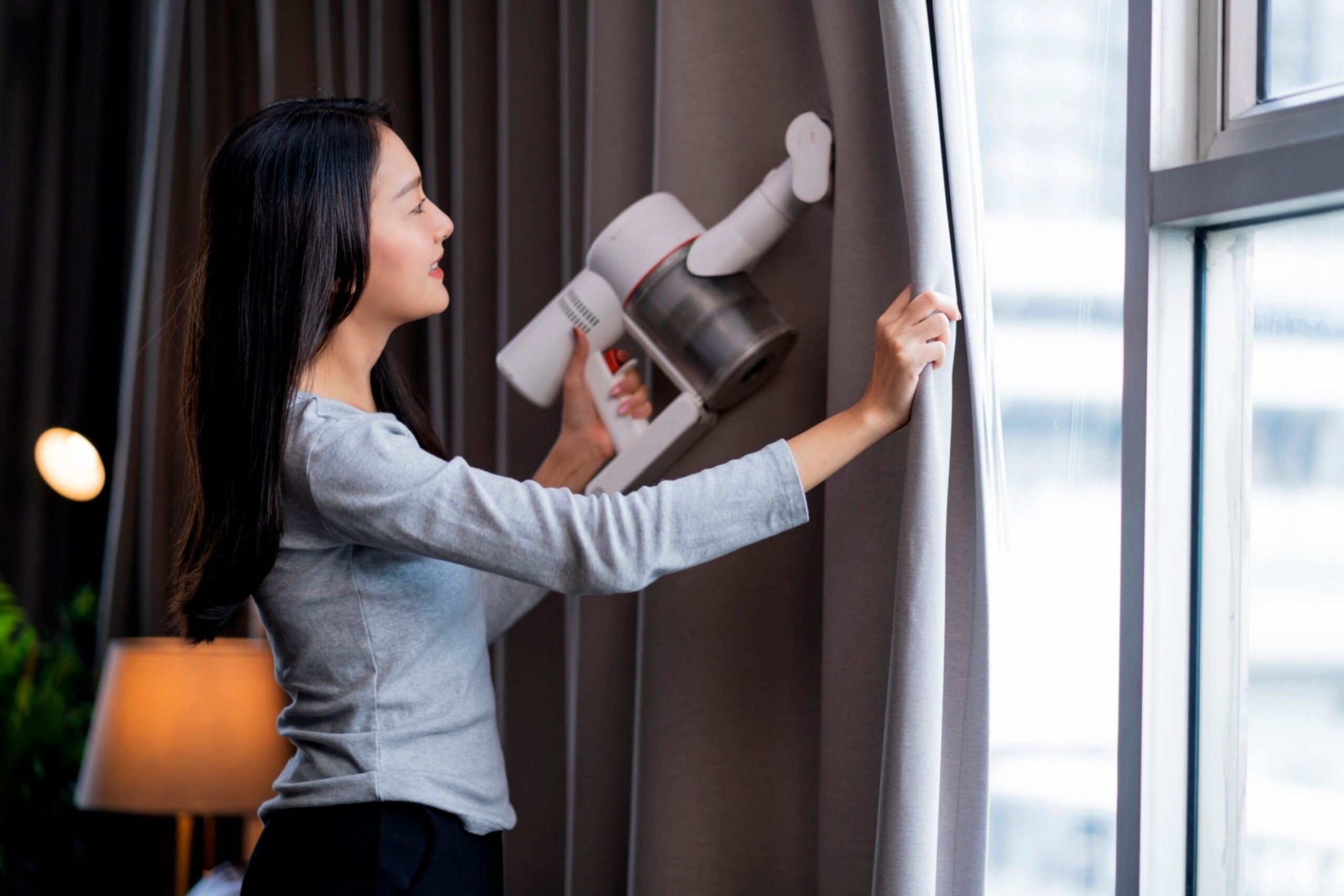 woman cleaning the curtain using vacuum