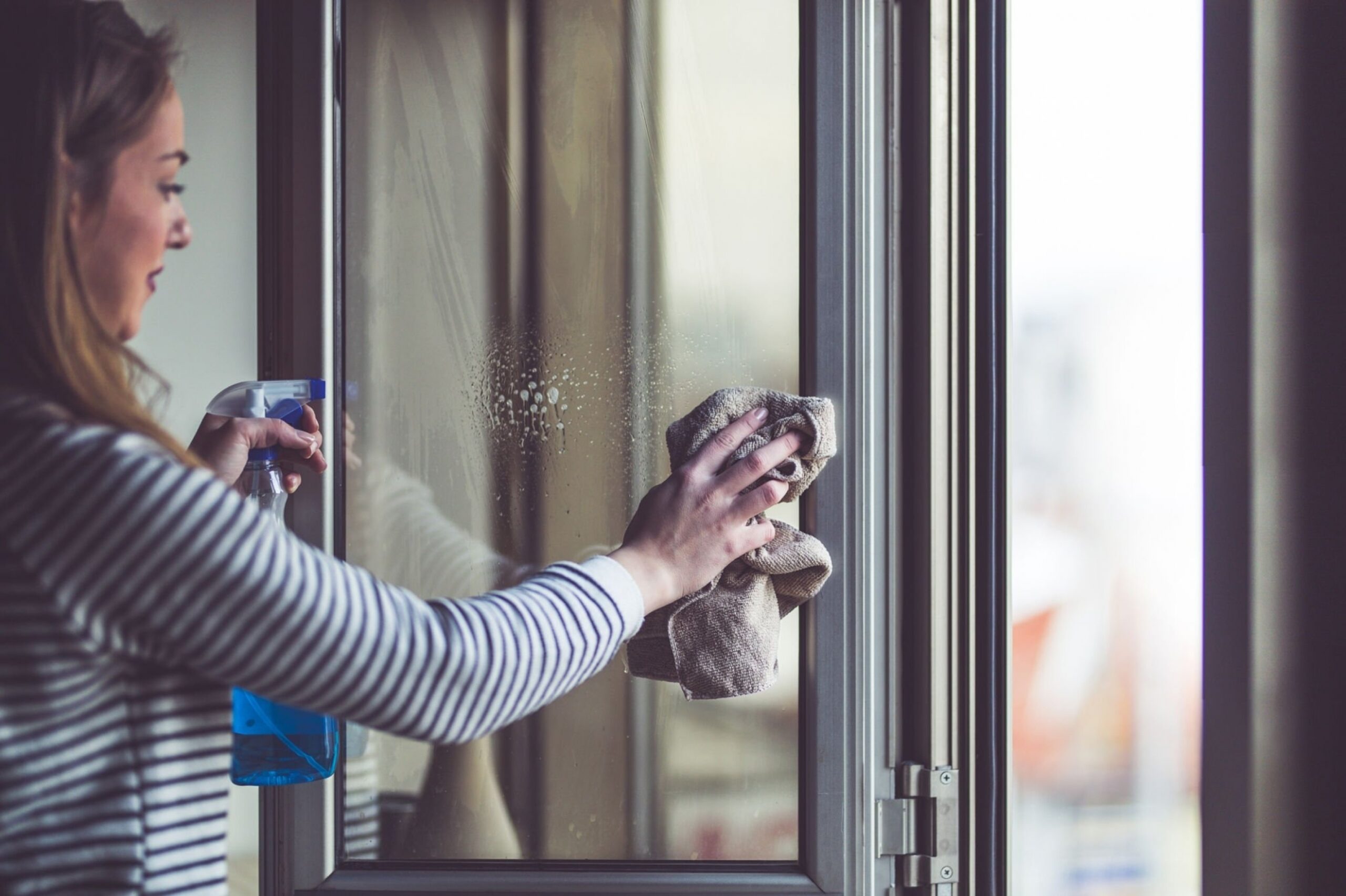 woman cleaning window glass at home