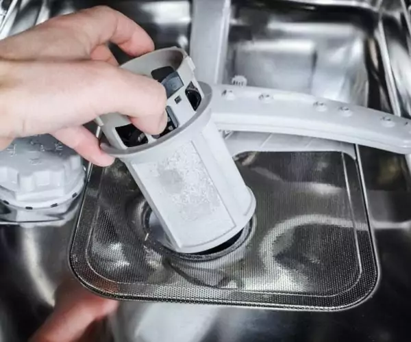Man cleans the filter in the dishwasher
