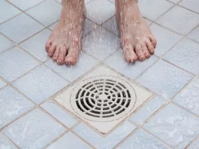 man standing near the shower drain