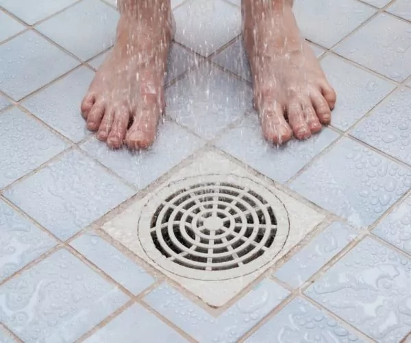 man standing near the shower drain