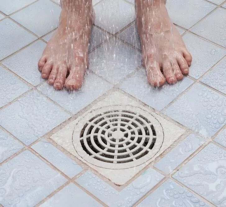 man standing near the shower drain