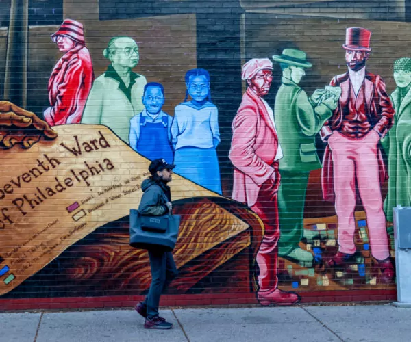 Man Walking by Mapping Courage Mural in Philadelphia