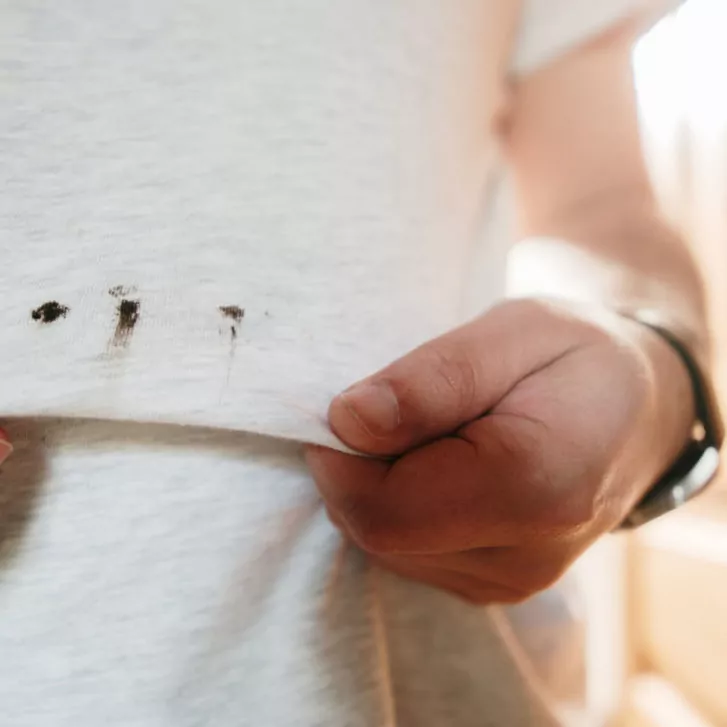 Two hands showing stains on a shirt