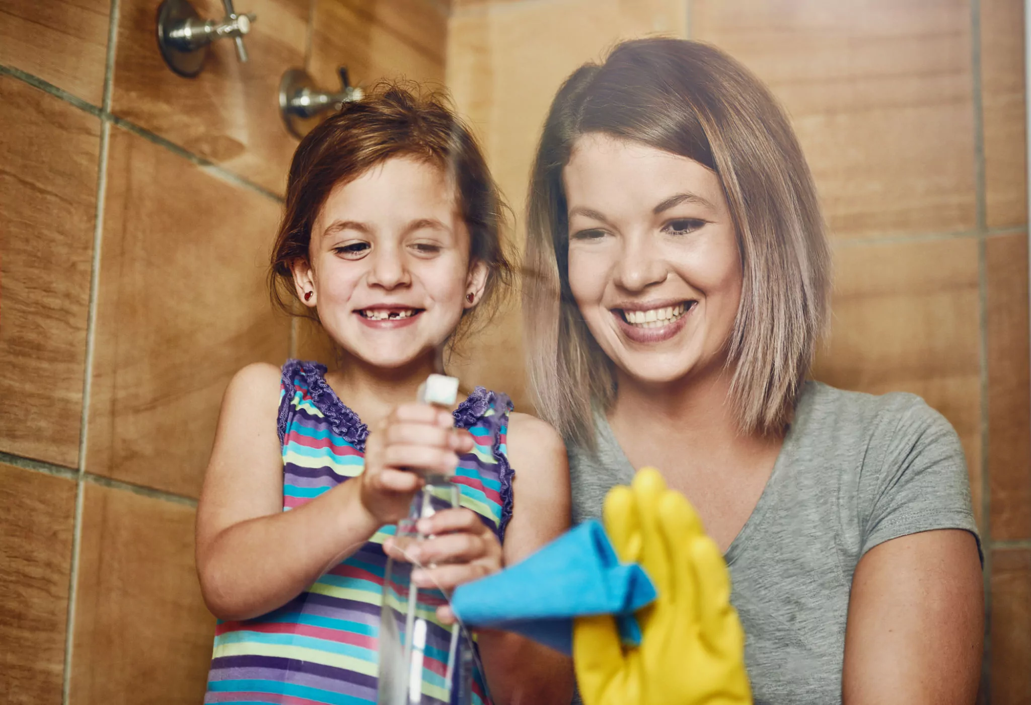 mother and her little daughter cleaning a bathroom together at home