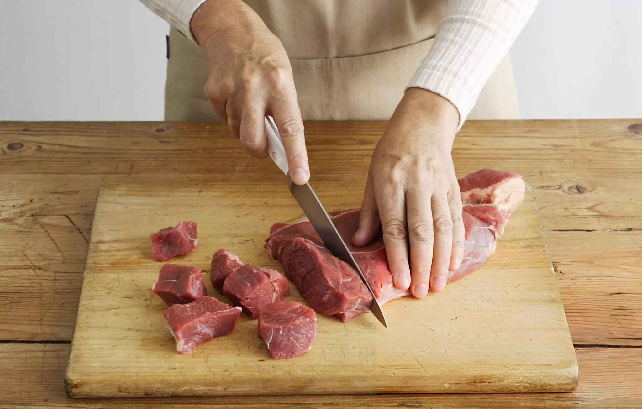 How to Clean Wood Cutting Board Cleanzen Image of a Woman Slicing Meat on Wooden Board