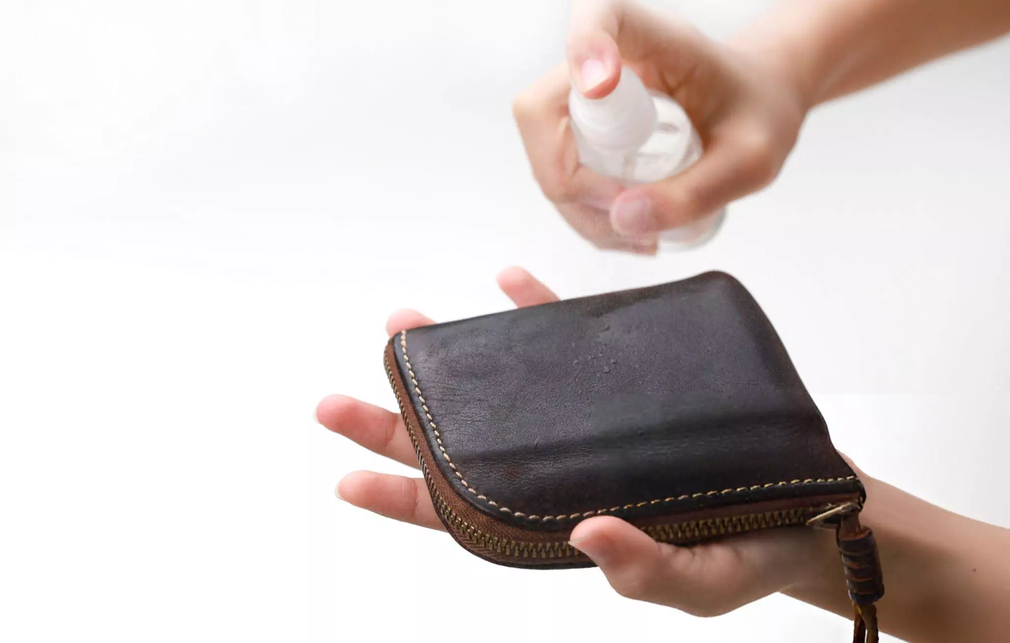 How to Clean Leather Purse Cleanzen Image of a Woman Cleaning Her Leather Purse with Disinfectant Spray