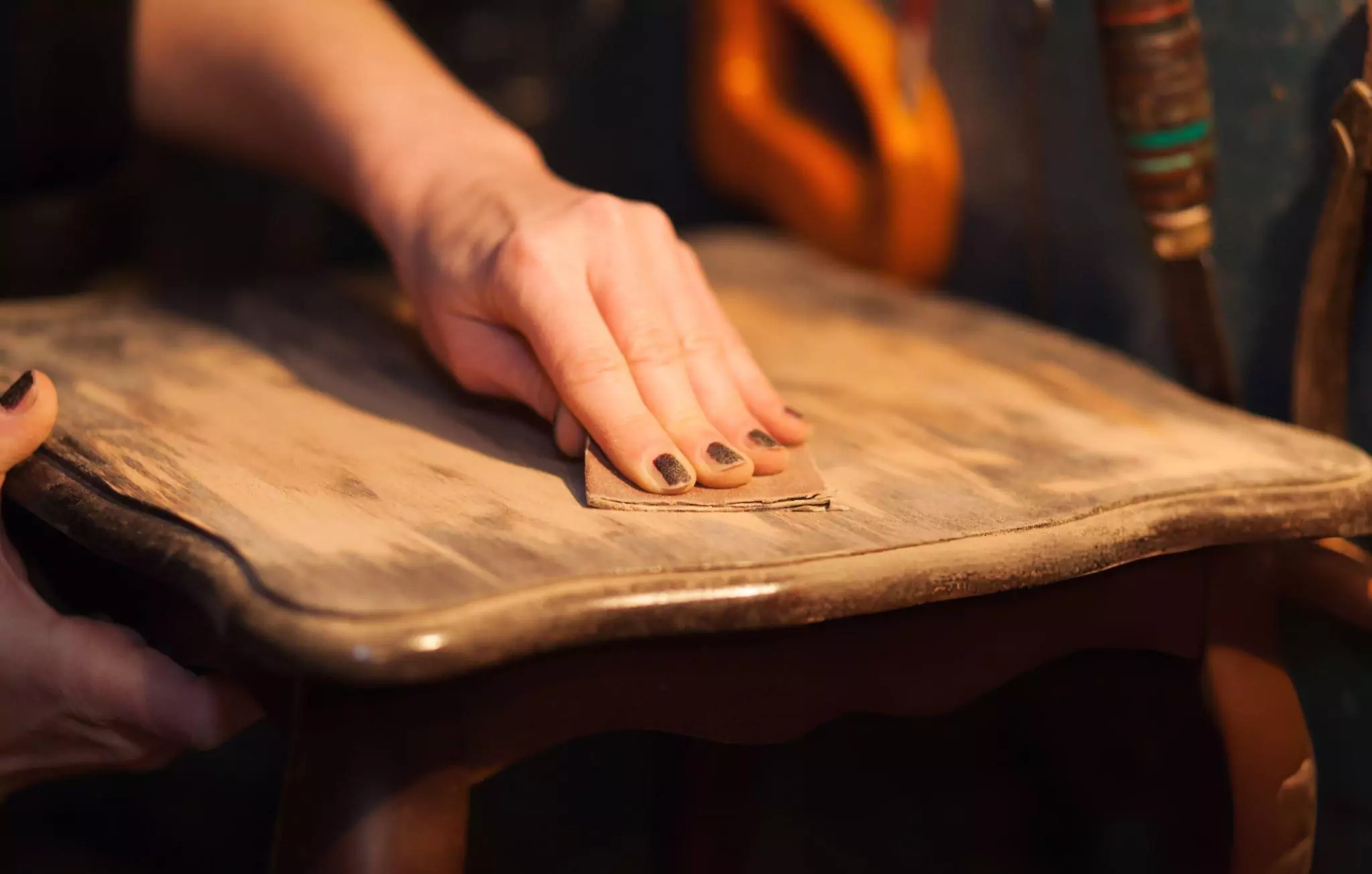 How to Remove Water Stains From Wood Cleanzen Image of a Woman Sanding Furniture with Sand Paper