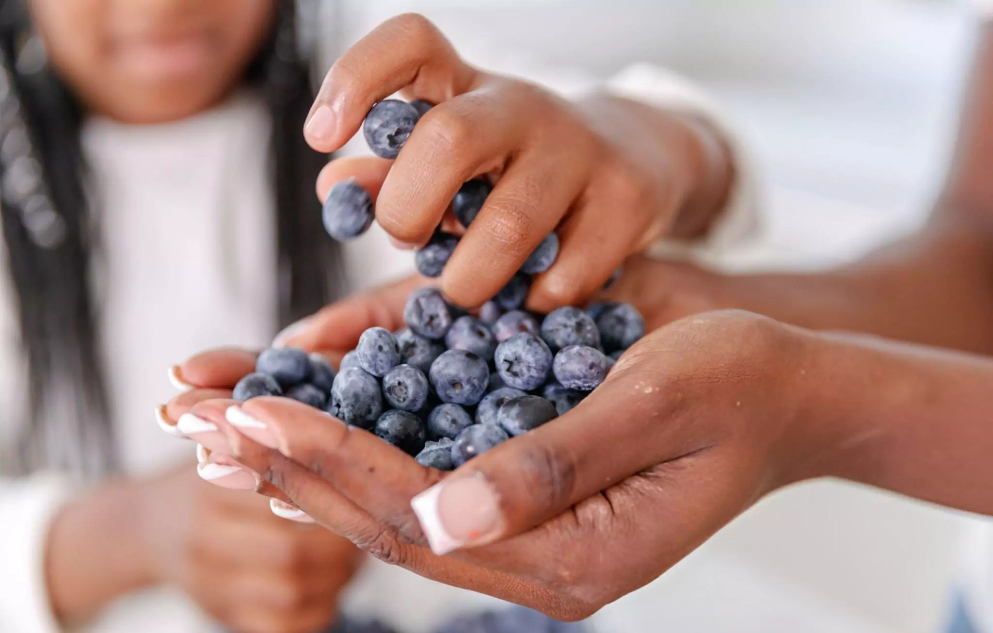 Cleaning Fruits with Baking Soda Cleanzen Image of a Girl Reaching for a Handful of Blueberries